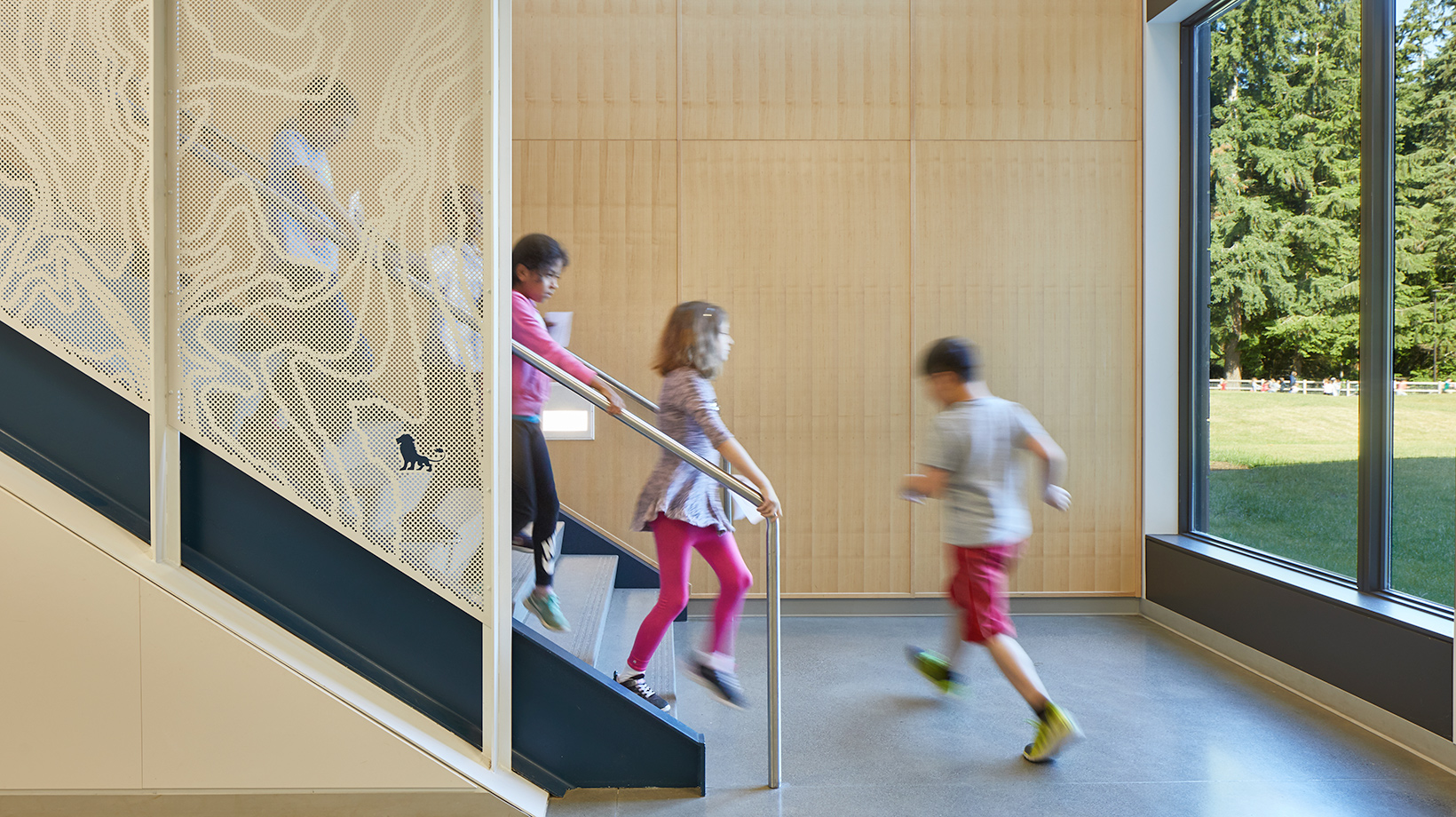 Children coming down an interior stair with a view to outside