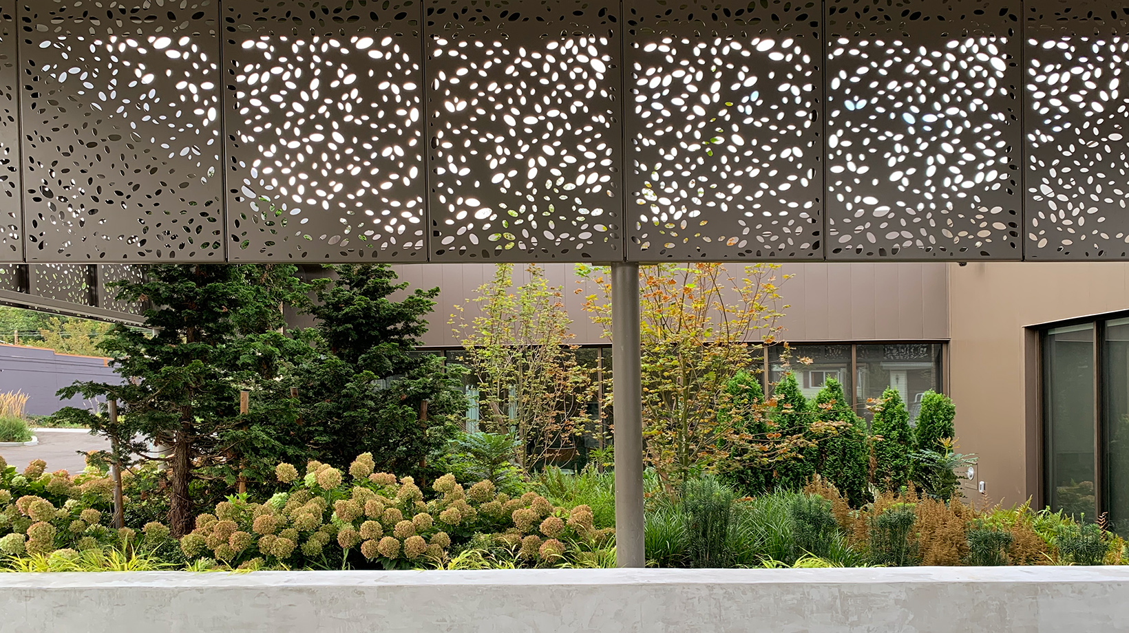 An elevation photo of punched metal screening and landscape beyond